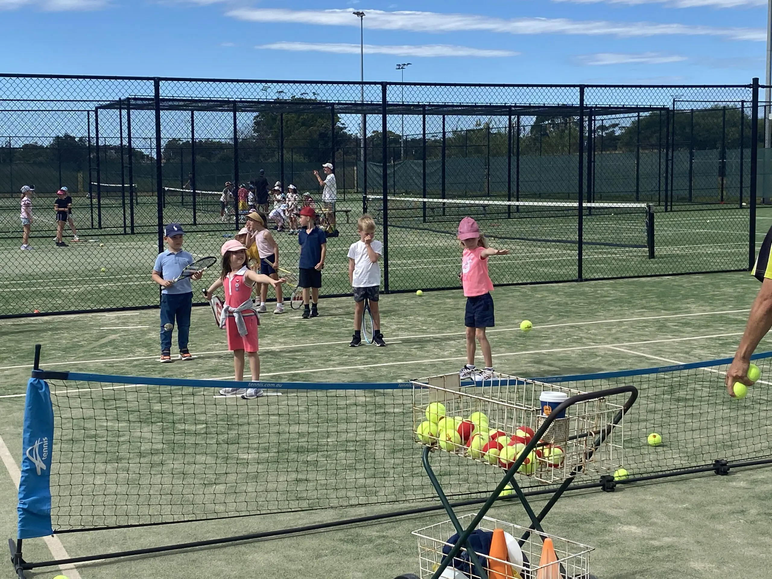 Young players on court at a Hot Shots junior tennis session, using stage-appropriate balls and equipment.